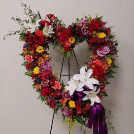 Heart-shaped floral wreath with red, white, and purple flowers on a stand