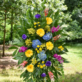 Tall standing floral spray with yellow, blue, purple, and pink blooms