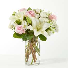 Pink roses and white lilies arranged in a clear glass vase
