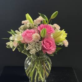 Pink roses and white lilies arranged in a clear glass vase