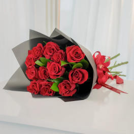 Bouquet of red roses wrapped in black paper with a red ribbon