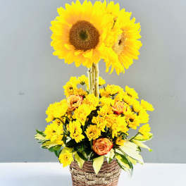 Yellow sunflowers and small yellow blooms in a woven basket