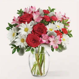 Bouquet of red roses, white daisies, and pink alstroemeria in a clear glass vase