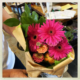 Bouquet of bright pink gerbera daisies with mixed blooms in brown paper