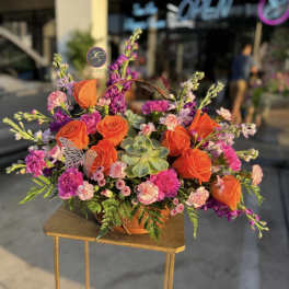Bright bouquet of orange roses and pink flowers in a low container