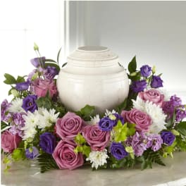 Purple and pink roses arranged around a white urn