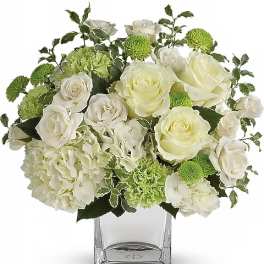 White roses and green chrysanthemums in a clear glass vase