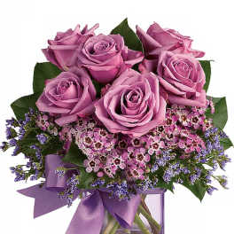 Lavender roses in a square glass vase with a purple ribbon