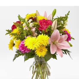 Mixed bouquet of pink lilies, roses, and yellow chrysanthemums in a glass vase