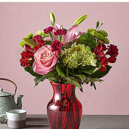 Pink and red flower arrangement in a red glass vase