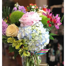 Mixed bouquet in a glass vase with a candle beside it