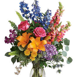 Colorful mixed bouquet with roses, lilies, and snapdragons in a glass vase