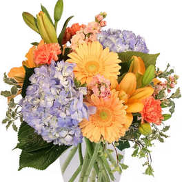 Mixed bouquet of orange and lavender flowers in a clear glass vase