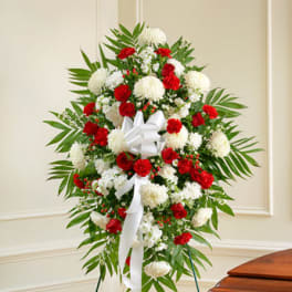 Standing spray of red carnations and white mums with a white bow on an easel