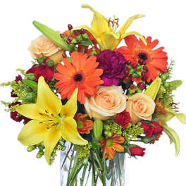 Mixed bouquet of lilies, roses, and gerbera daisies in a clear glass vase