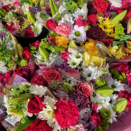Assorted bouquets of roses, daisies, and lilies in colorful wrapping