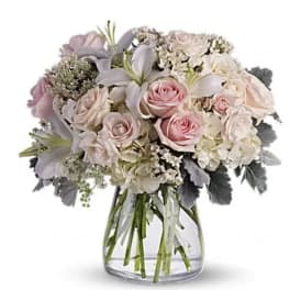 Blush and white bouquet of roses and lilies in a clear glass vase