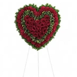 Heart-shaped standing floral tribute with red roses and greenery
