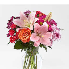 Pink lilies and mixed roses in a clear glass vase