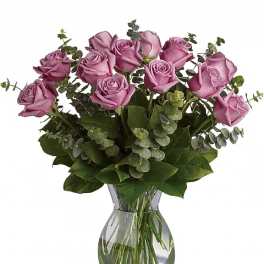 Pink roses arranged in a clear glass vase with greenery