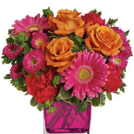 Bouquet of orange roses and pink daisies in a magenta glass vase