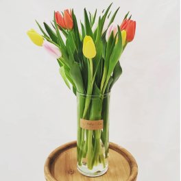 Glass vase of colorful tulips on a wooden stand