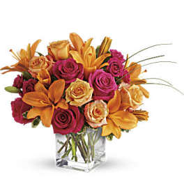 Bouquet of orange lilies and pink roses in a clear square vase