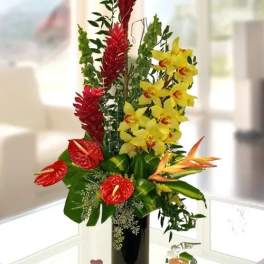 Tropical flower arrangement with red anthuriums and yellow orchids in a black vase