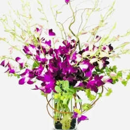Purple orchids in a glass vase with butterfly accents