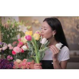Woman holding a bouquet of tulips in pink, yellow, and white