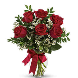 Bouquet of red roses with small white filler flowers in a glass vase