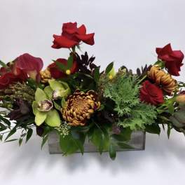 Long floral arrangement with red roses, green orchids, and chrysanthemums in a rectangular container