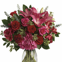 Pink lilies and red roses arranged in a clear glass vase