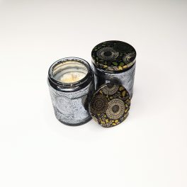 Two decorative candles in patterned glass jars with lids