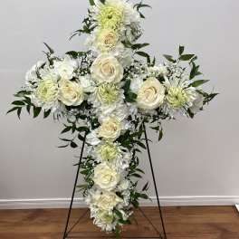 White floral cross on a black stand with roses and chrysanthemums