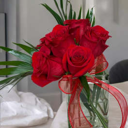 Red roses in a clear glass vase with a red ribbon