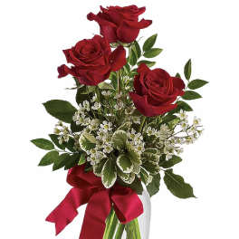 Red roses in a clear glass vase with a red ribbon