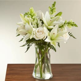 White lilies and roses arranged in a clear glass vase
