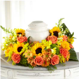Sunflower and rose arrangement around a white urn