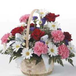 Basket arrangement with red roses, pink carnations, and white daisies