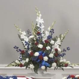 Red, white, and blue floral arrangement in a white vase