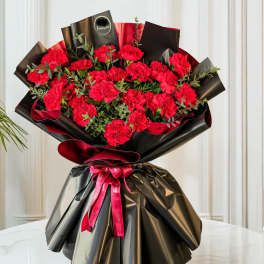Bouquet of red carnations wrapped in black paper with a red ribbon