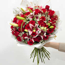 Bouquet of red roses and pink lilies wrapped in white paper
