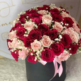 Bouquet of red and blush roses in a black hat box with a pink ribbon