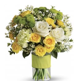 Yellow and white roses with green mums in a glass vase
