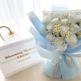 Bouquet of white roses and small daisies wrapped in pale blue paper