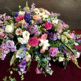 Large mixed floral arrangement with roses, orchids, and lilac blooms