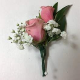 Pink rose boutonniere with white baby's breath and green leaves