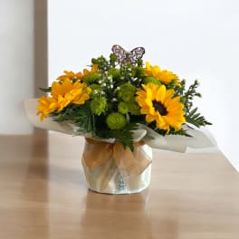 Yellow sunflower bouquet in a wrapped vase with a ribbon