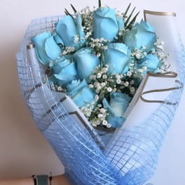 Bouquet of blue roses with white baby's breath in blue mesh wrap